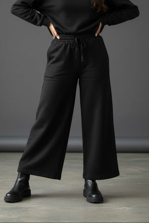 Woman wearing Pavline black wide leg drawstring lounge pants with relaxed fit and premium casual style.