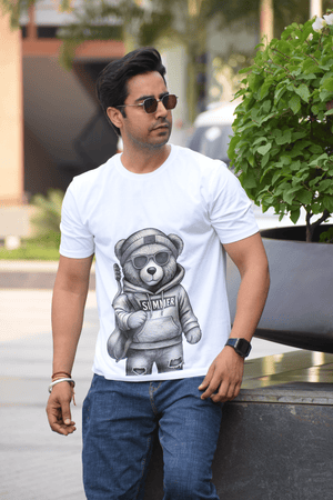 Man wearing a white t-shirt with a bear graphic and sunglasses outdoors.