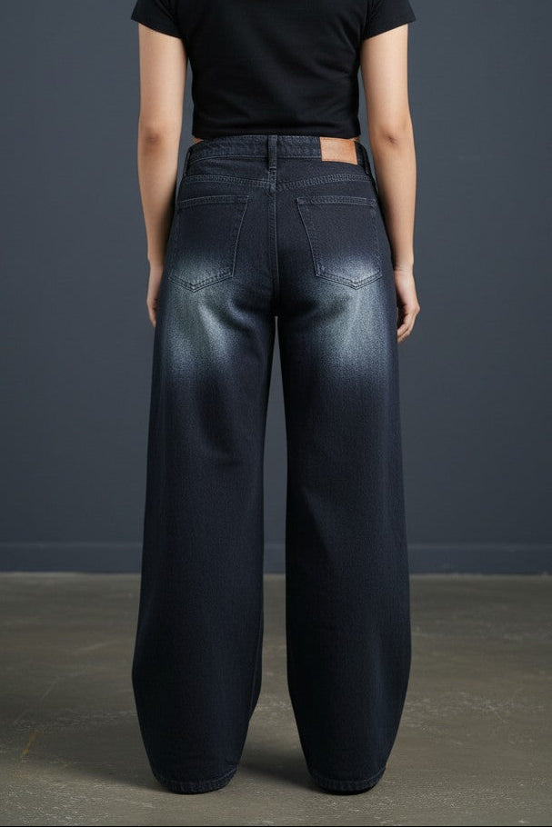 Woman wearing Pavline washed black high waist wide leg denim jeans paired with a black crop top for a modern casual streetwear look.