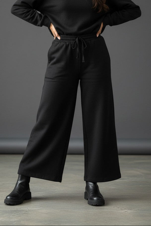 Woman wearing Pavline black wide leg drawstring lounge pants with relaxed fit and premium casual style.