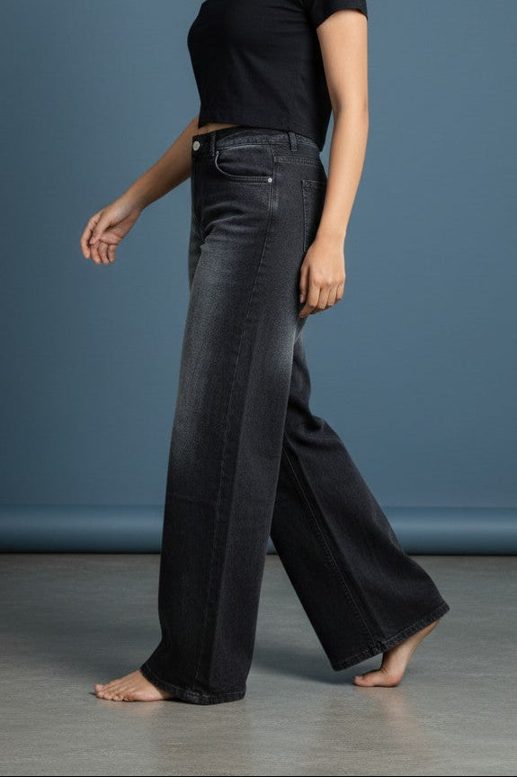 Woman wearing Pavline washed black high waist wide leg denim jeans paired with a black crop top for a modern casual streetwear look.