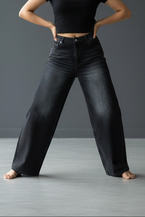 Woman wearing Pavline washed black high waist wide leg denim jeans paired with a black crop top for a modern casual streetwear look.