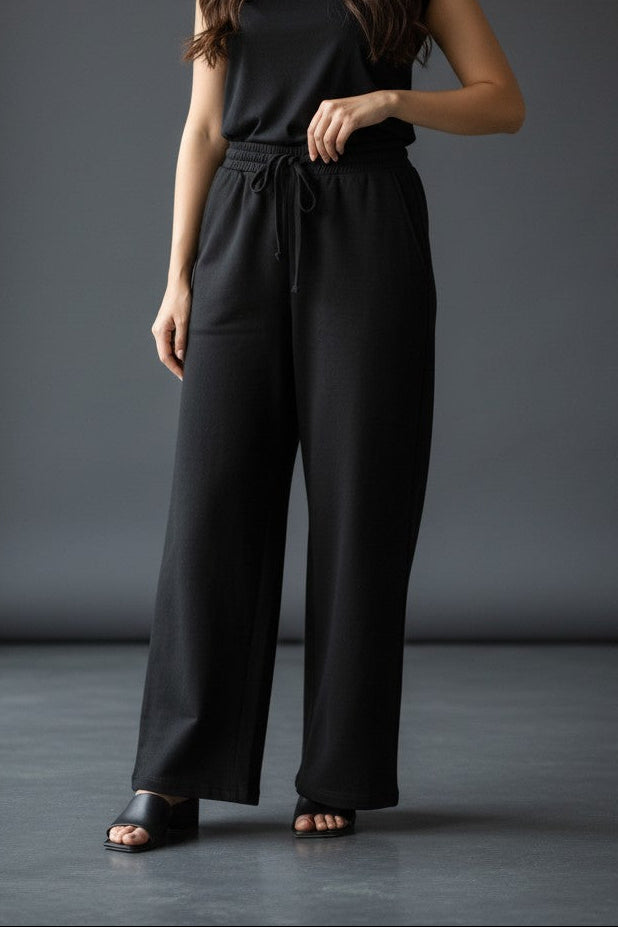 Woman wearing Pavline black wide leg drawstring lounge pants with relaxed fit and premium casual style.