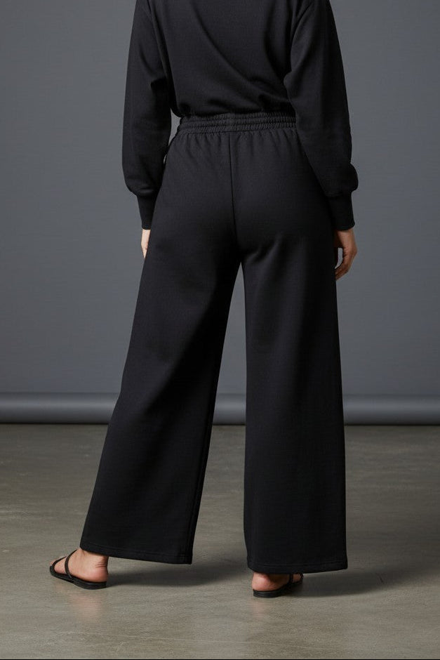 Woman wearing Pavline black wide leg drawstring lounge pants with relaxed fit and premium casual style.