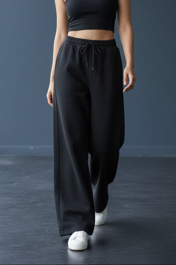 Woman wearing Pavline black wide leg drawstring lounge pants with relaxed fit and premium casual style.