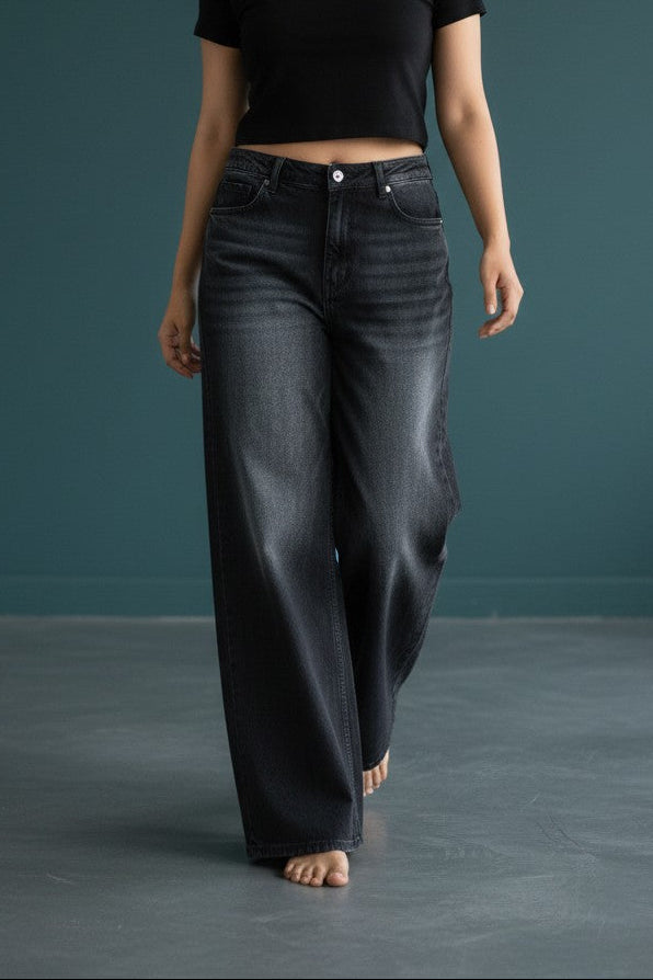 Woman wearing Pavline washed black high waist wide leg denim jeans paired with a black crop top for a modern casual streetwear look.